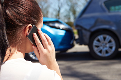 Woman on phone in front of car accident